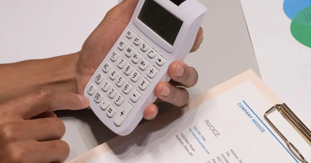 Manos con una calculadora junto a una factura