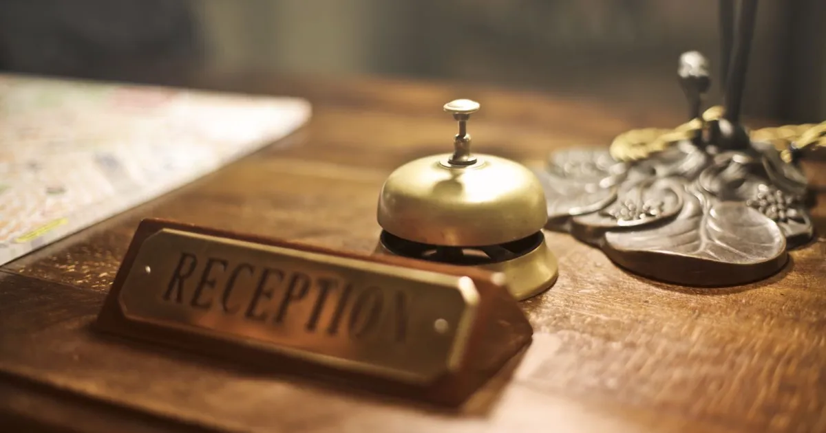 Placa de recepción y timbre dorado sobre un mostrador de madera